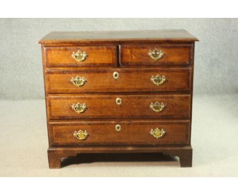An 18th century George III oak chest of two short over three long graduated crossbanded drawers, with brass swing handles and