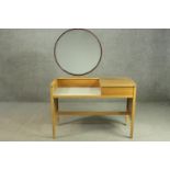 An E Gomme G-Plan oak dressing table, with a circular mirror, over a white recess, flanked by a