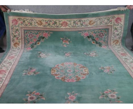 A Chinese carpet with central floral medallion and spandrels on a jade ground within stylised scrolling foliate borders. L.36