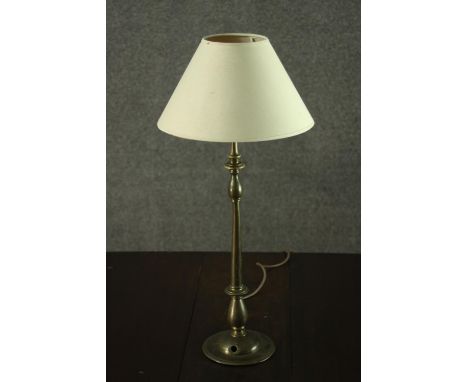 A turned brass table lamp, with an ivory coloured shade. H.56 W.25cm. 