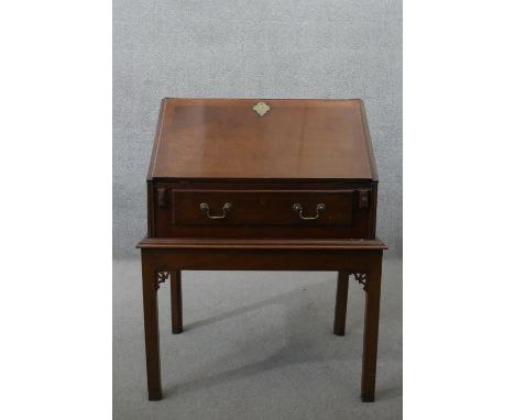 A George III mahogany bureau on stand, the fall front opening to reveal a central door, pigeonholes and four drawers over a w