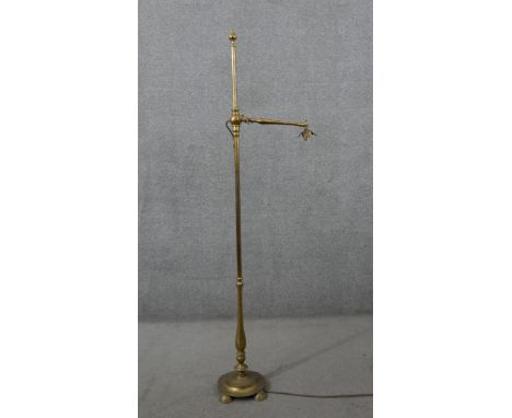 A Victorian brass adjustable floor standing reading lamp, with leaf detail to the fitting, on a circular base with four feet.