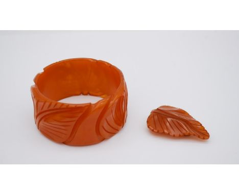 An Art Deco carved amber bakelite leaf design bangle and matching leaf scarf clip. 