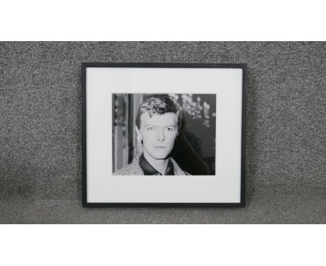 A framed black and white photograph portrait of David Bowie, with Brider &amp; Bull label verso. H.32 W.36.5cm 