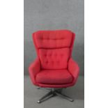 A mid 20th century swivel armchair, upholstered in red fabric, with buttoned back and seat, on a