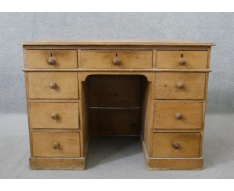 A Victorian pine kneehole desk, the rectangular top with a moulded edge, over an arrangement of nine drawers with knob handle