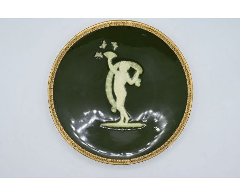 Minton Pate-sur-pate plate a green glaze panel with a cupid playing with butterflies and a gilt rim, initialled "SH" below th