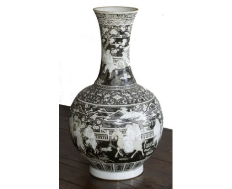 A CHINESE PORCELAIN BOTTLE VASE, with unusual white enamel on a grey/black background, decorated with a procession of figures