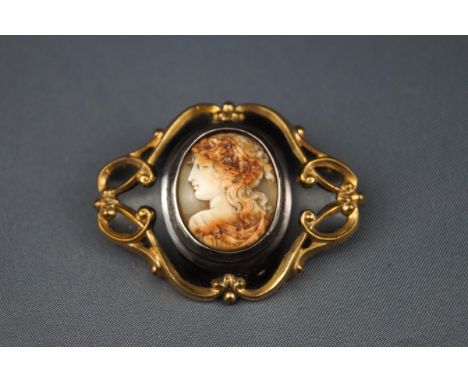 A Victorian black enamel and gold-plated shaped-oval mourning brooch, later applied at the centre with an oval shell cameo de
