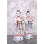 A pair of Chinese famille rose figures of ladies bearing a vase, Qianlong