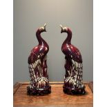 A pair of Chinese flambe-glazed models of phoenix on wooden stands, 19th/20th C.