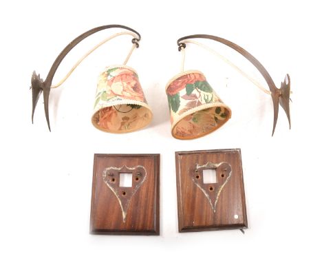 Pair of Arts &amp; Crafts style brass wall lights, the arms of strap form on a heart-shaped bracket, with rectangular mahogan