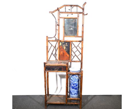 A bamboo hall stand with a blue and white Chinese porcelain stick stand, a small rectangular mirror surrounded by an arrangem