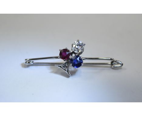 Ladies Sapphire, Diamond & Ruby Bar Brooch. Applied round cut diamond, sapphire and ruby set in a 'club' shaped mount on whit