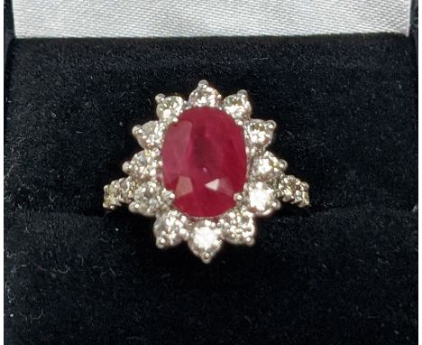 AN 18CT WHITE GOLD RUBY AND DIAMOND CLUSTER RING, with diamond set shoulders, the central oval cut ruby of approximately 3.08