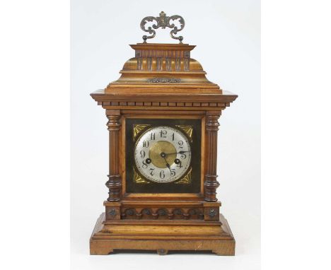 An early 20th century continental walnut cased eight-day mantel clock, the silvered chapter ring showing Arabic numerals, the