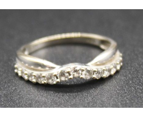 A modern white metal and diamond set half hoop ring, arranged as 13 small graduated brilliants, to a whalebone band, stamped 