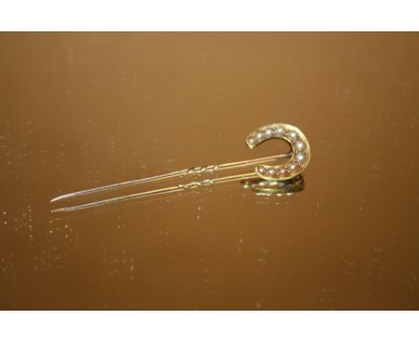 AN UNMARKED YELLOW METAL HORSESHOE SHAPED STICK PIN SET WITH SEED PEARLS