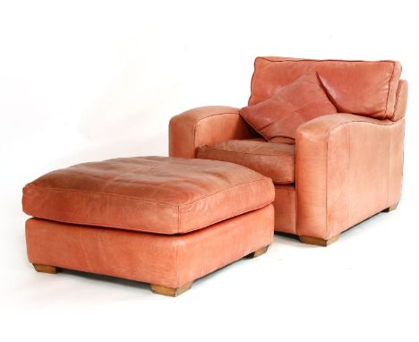 A modern red leather armchair, and pouffe