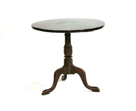 A George III mahogany tilt top tea table, the circular top over a turned baluster base on a tripod base on shaped pad feet, 7