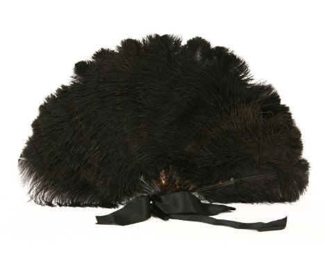 A black ostrich feather fan, early 20th century, with tortoiseshell sticks and guard stick, with a satin bow to the bale, in 