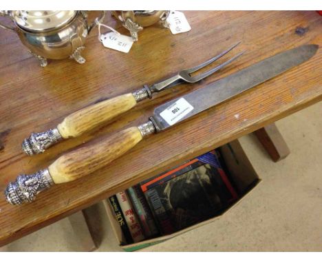 A bone handled carving set with white metal finials and bands with bull head decoration.
