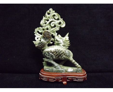 Chinese Jade carving on wooden stand. Qilin hooved mythical beast breathing smoke and fire, head turned. Amongst the smoke on
