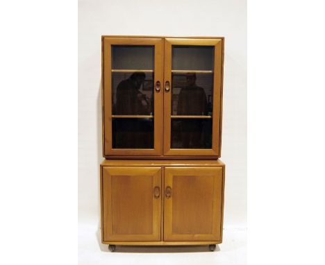 Mid-century modern Ercol light elm bookcase cabinet, the two glazed doors with shelves, the base of two cupboard doors with c