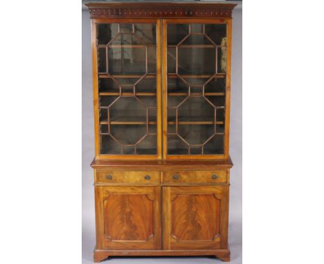A late 19th century mahogany tall bookcase fitted three adjustable shelves enclosed by a pair of glazed doors, two frieze dra