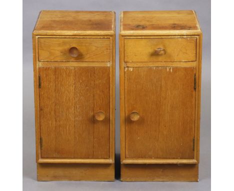 A pair of Meredew light-oak bedside cupboards, each fitted with a short drawer above a single cupboard, with turned wooden ha