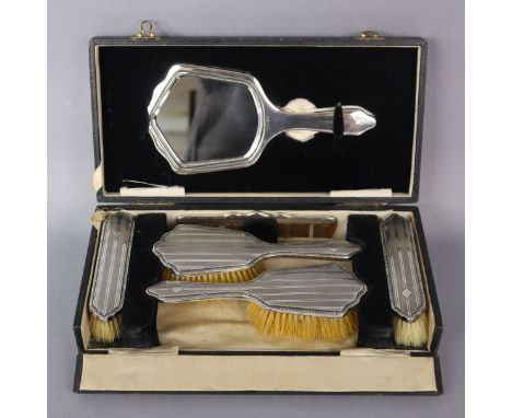 A George V engine-turned silver mounted dressing table set of hand mirror, two hairbrushes, two clothes brushes, &amp; a comb