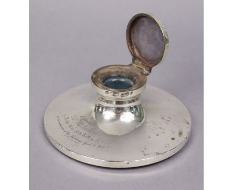 A George V silver capstan inkwell with hinged cover &amp; engraved inscription, 16.3cm dia.; Birmingham 1936. (w.a.f.). 