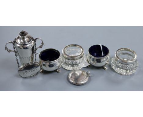 A pair of George V silver salts with liners, a pair of silver mounted glass salts, a silver pill box, a silver wine label and