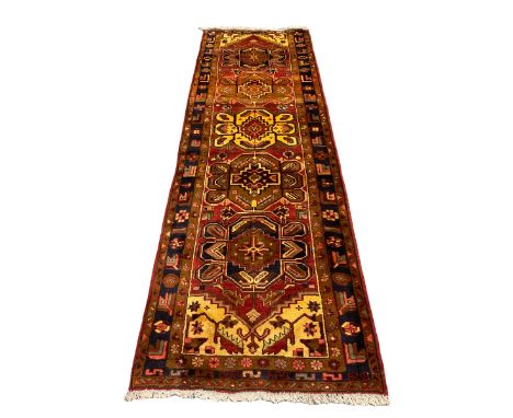 Persian Heriz golden red ground runner, the field decorated with five medallions and geometric motifs, repeating geometric de