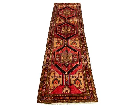 Persian Karajeh red ground runner, the field set with three trailing geometric medallions, decorated all over with stylised p