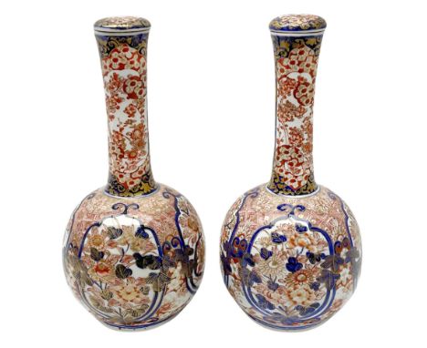 Pair of late 19th century Japanese Imari porcelain bottle vases with covers, painted with shaped reserves of peonies, chrysan