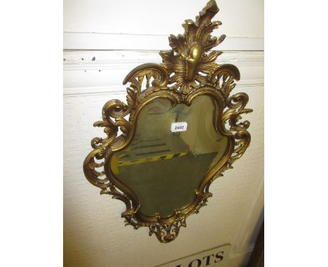 19th Century gilt brass cartouche wall mirror with a bevelled plate together with a brass table lamp