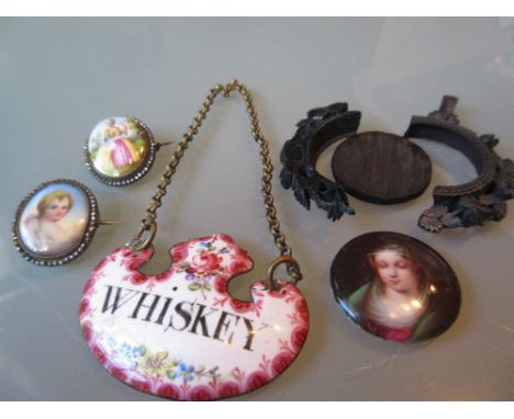 Two small 19th Century enamelled mother of pearl and cut steel brooches, an enamel whisky label and a miniature porcelain pla