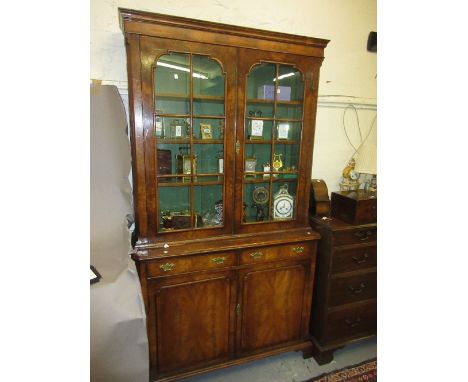 Early 20th Century walnut bookcase in 18th Century style, the moulded cornice above a pair of bar glazed doors enclosing shel