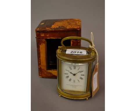 Small oval brass cased carriage clock by Goldsmiths and Silversmiths, London with travel case and key