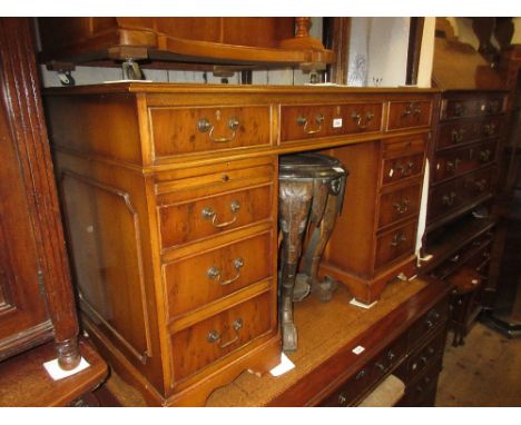 Reproduction yew wood pedestal desk having brown leather inset top above an arrangement of nine drawers with brass swan neck 
