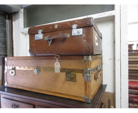 Tan leather travel trunk with canvas cover together with another simulated leather trunk