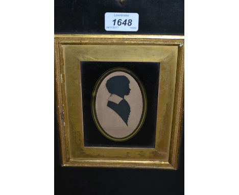 19th Century silhouette portrait of a boy together with a gilt framed coloured print, figures in landscapes