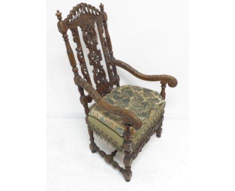 A late 17th century style (a good reproduction) open-armed carved walnut armchair of generous proportions; the pierced top-ra