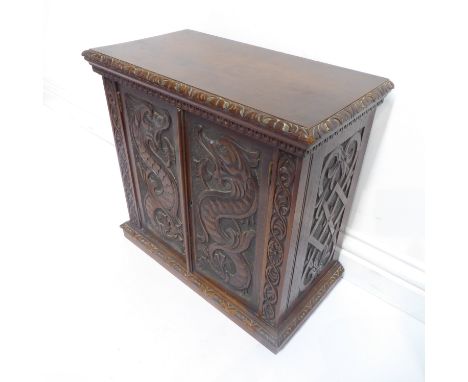 A good late 19th century mahogany table cabinet&nbsp;– the two panelled doors carved in relief with fire-breathing marine-typ