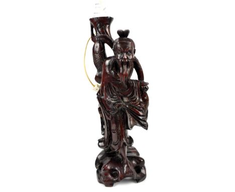 A 20th century Asian hardwood carving of a gentleman holding a fish, made into a lamp base, height 60cm.