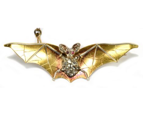 A yellow and white metal Art Nouveau bat brooch, the bat's body covered with rough cut diamonds and red cabouchon eyes, with 