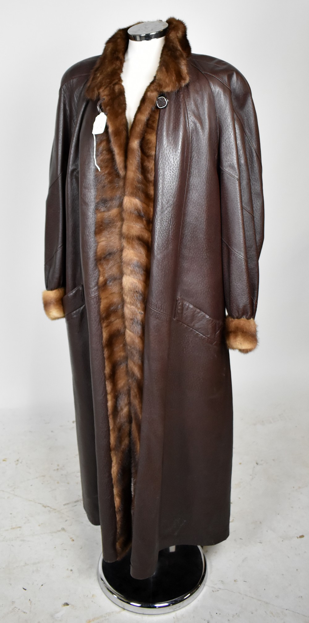 A dark brown leather full length coat with fur lining in dark brown and fur trim around the colla