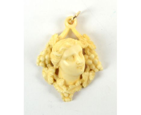 A 19th century ivory pendant carved as the bust of a Classical-style lady amongst vines, leaves and grapes, with yellow metal