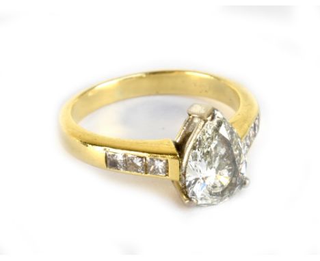 A yellow metal diamond solitaire ring, the principal pear cut stone weighing approx 1.31cts with six further diamonds to the 